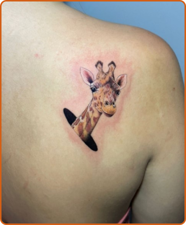 Tatuagem realista de girafa com o rosto saindo de um buraco.